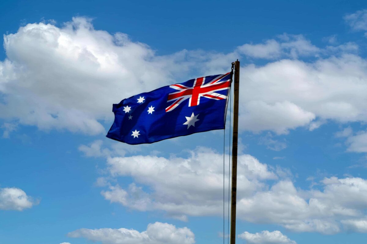 Close-up of an Australian flag with a blue sky in the background, symbolizing USA to Australia dog relocation planning.